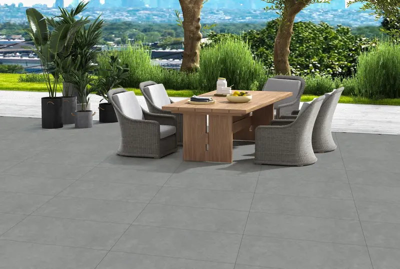 Outdoor terrace with grey matt floor tiles, a dining table and a garden view